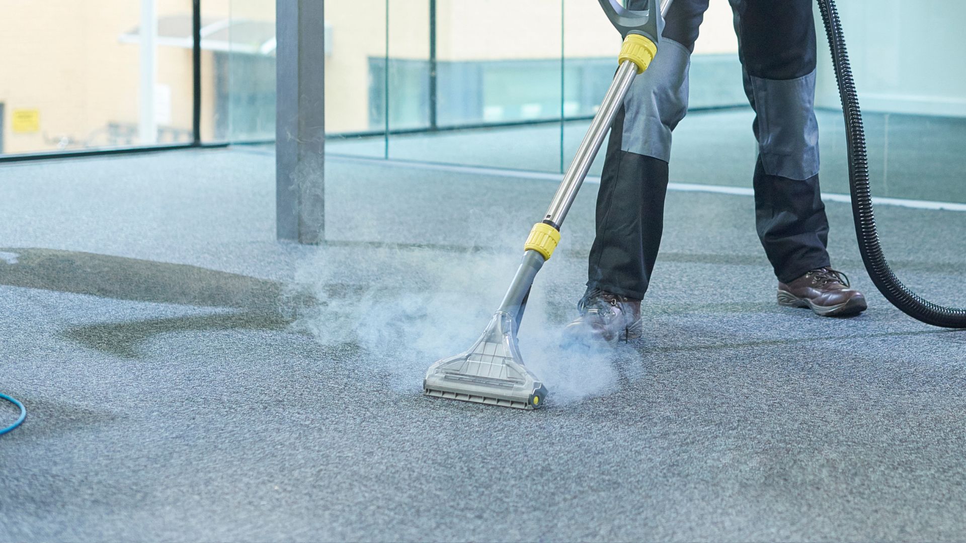 A man using a vacuum cleaner to clean a carpet.