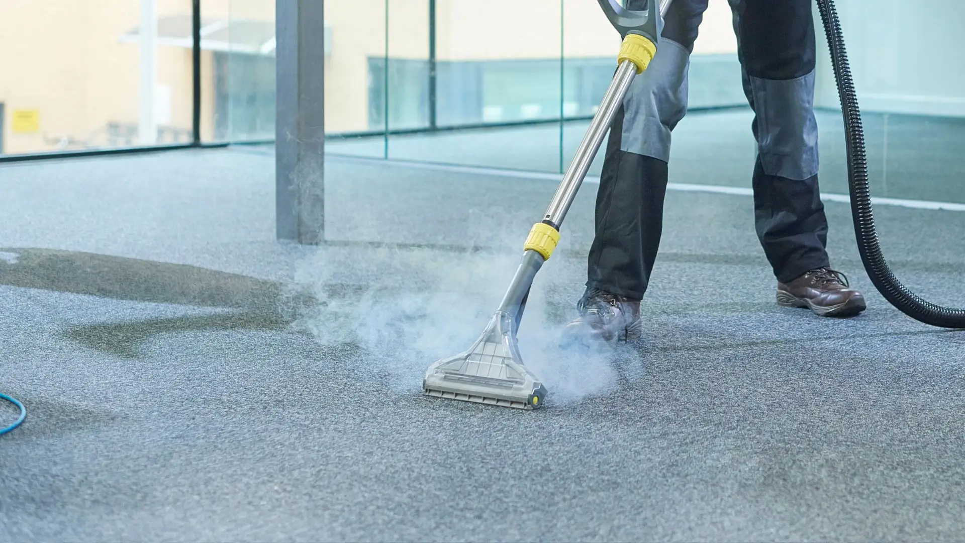 A man using a vacuum cleaner to clean a carpet.